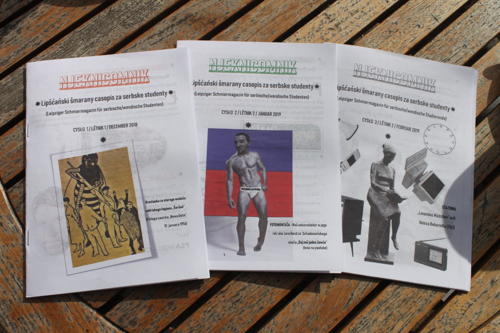 Drei Ausgaben der sorbischen Studierendenzeitschrift liegen auf einem Holztisch.