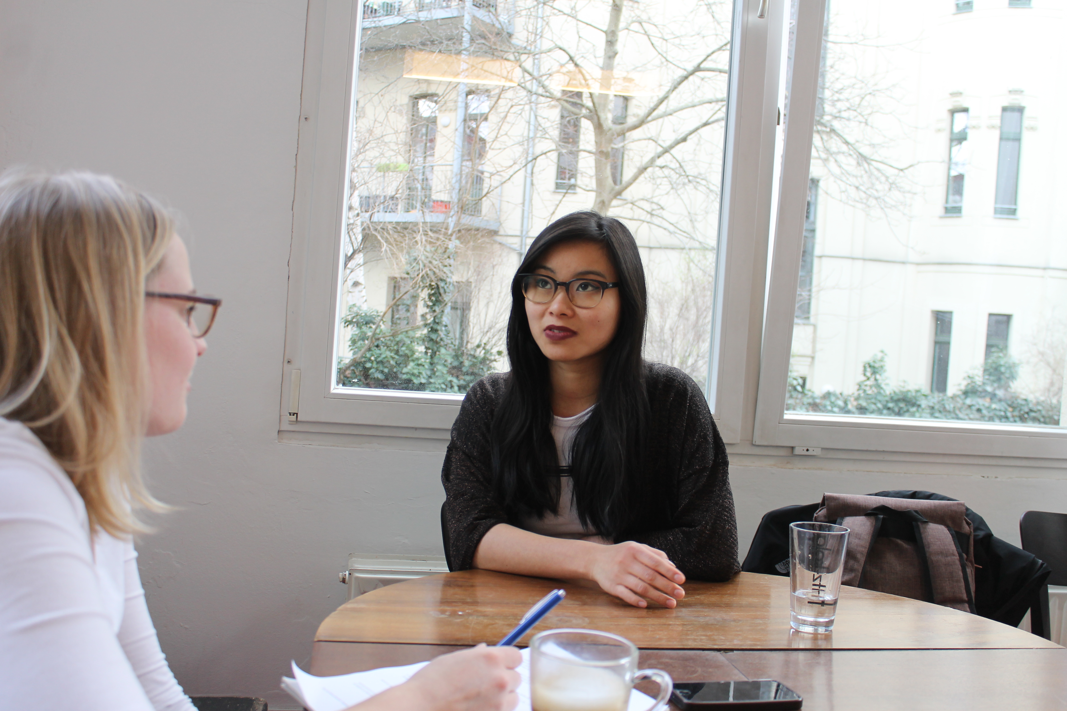 Bloggerin Nhi Le sitzt an einem Tisch; links im Bild student!-Redakteurin Hanna Lohoff